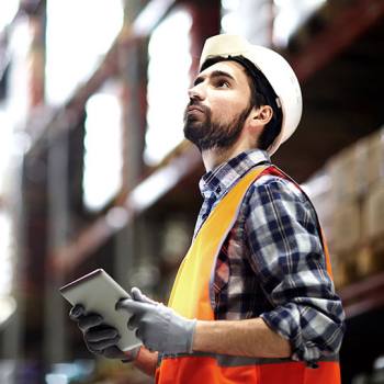 Logistiikka man wearing hard hat looking at tablet