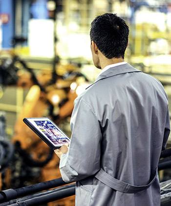 Simplify supply chains man surveying a workspace and holding a tablet